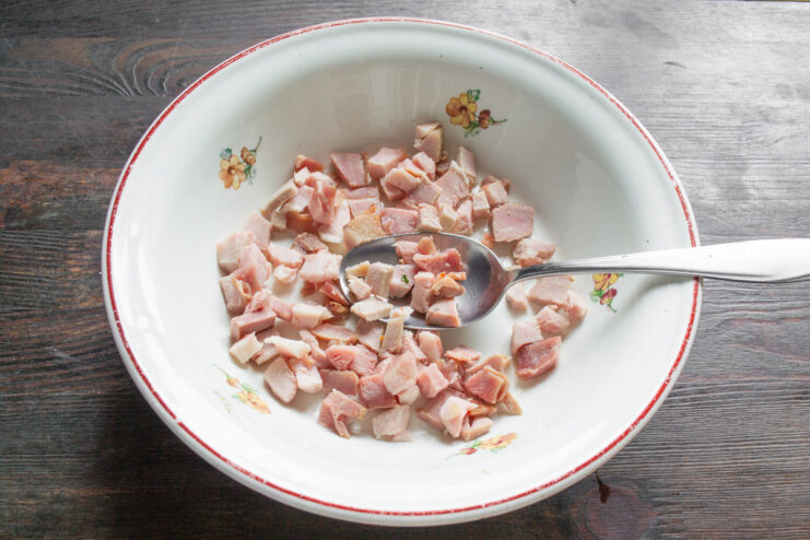 Dicing Lean Ham for the Omelet Filling Close-up of lean ham being diced into small cubes on a cutting board.