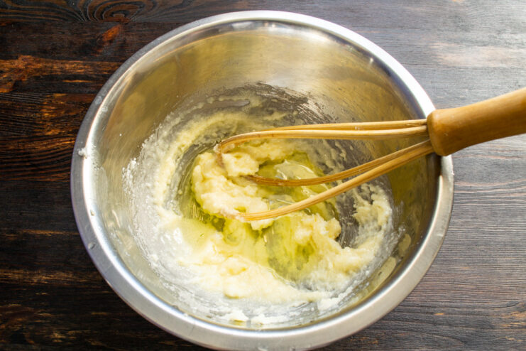 Adding egg white to the butter and sugar mixture Adding an egg white to the creamed butter and sugar in a bowl.