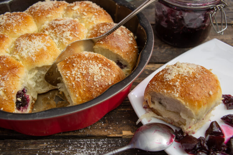 A freshly baked pull-apart pie with a jam filling, presented whole on a wooden board.