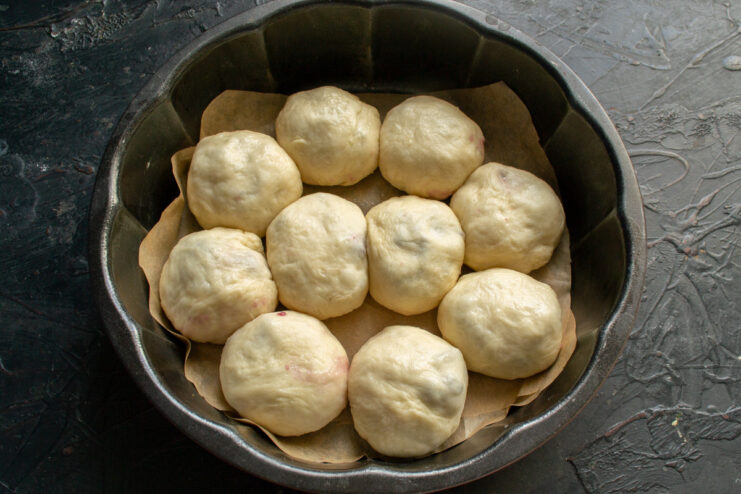 Preparing the baking pan with parchment paper for easy removal A round metal baking pan being lined with a sheet of parchment paper.