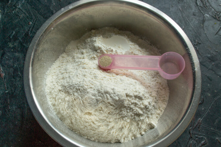First step for the dough: combining dry ingredients A white bowl containing flour and yeast being mixed together.