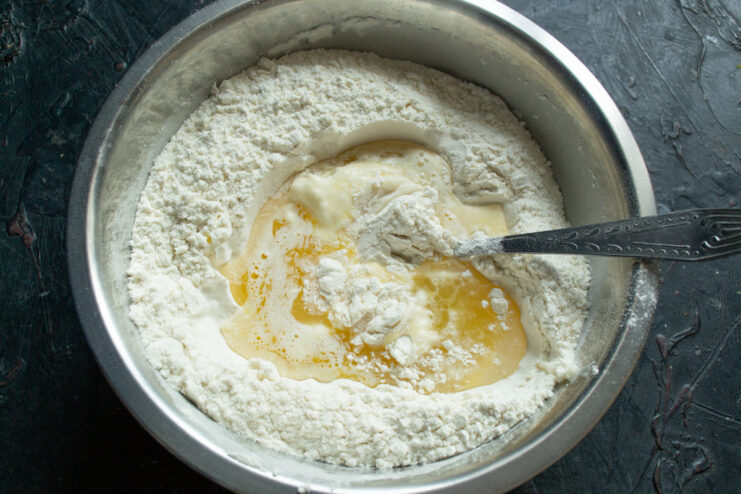 Combining wet and dry ingredients to form the dough Wet ingredients being poured into a well in the flour mixture in a bowl.
