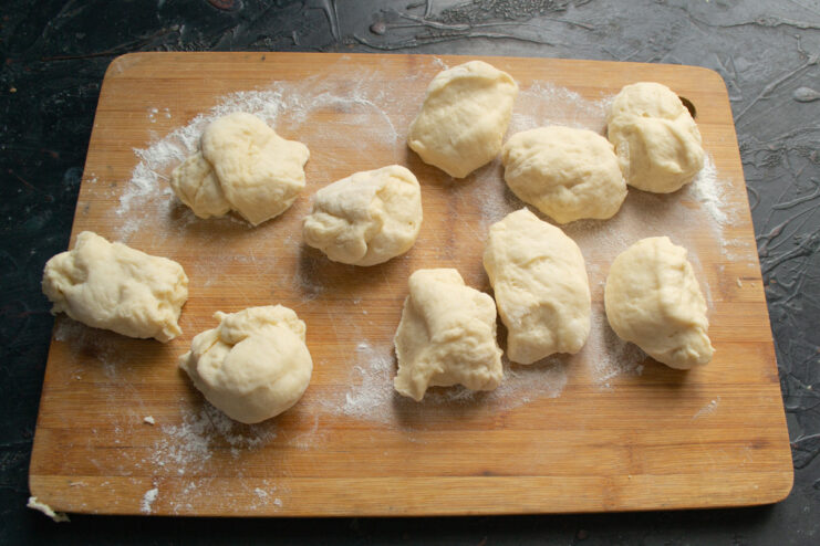 Portioning the dough for individual buns A large piece of dough cut into smaller, equal-sized portions.