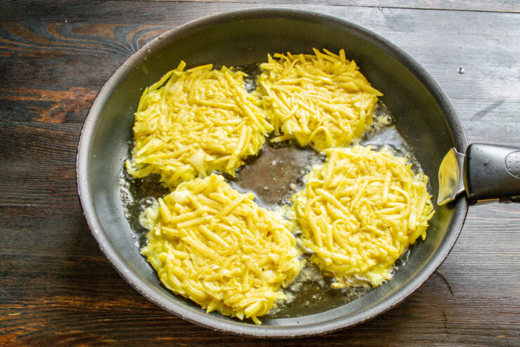 Frying the Vegetable Fritters to Golden Perfection Portions of vegetable fritter batter being spooned into a hot skillet with oil.
