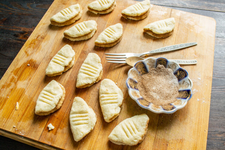 Folding the cinnamon-coated dough to create the classic cookie shape. A piece of cookie dough folded in half, with the cinnamon-sugar coating on the inside.