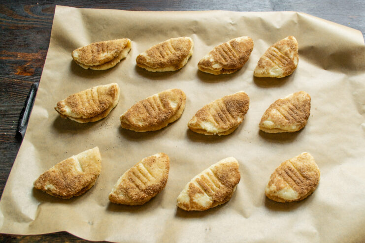 Placing the prepared cookies on a baking sheet before they go into the oven. Shaped tvorog cookies arranged on a parchment-lined baking sheet, ready for baking.