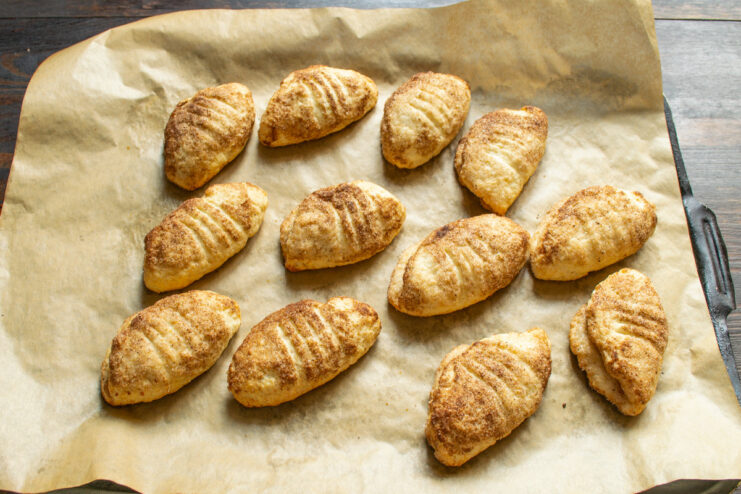 Baking the tvorog cookies until they are perfectly golden and cooked through. A baking sheet with tvorog cookies inside a lit oven, baking to a golden color.