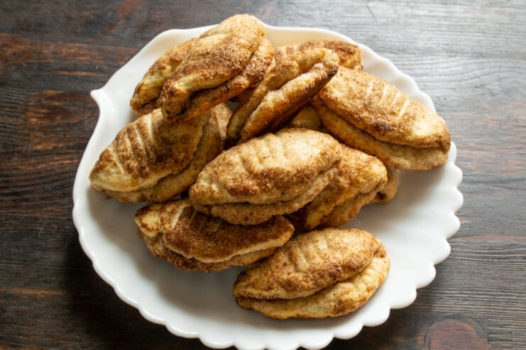 Storing the freshly baked tvorog cookies to keep them fresh. A basket filled with freshly baked, golden-brown Tvorog and Cinnamon Cookies.