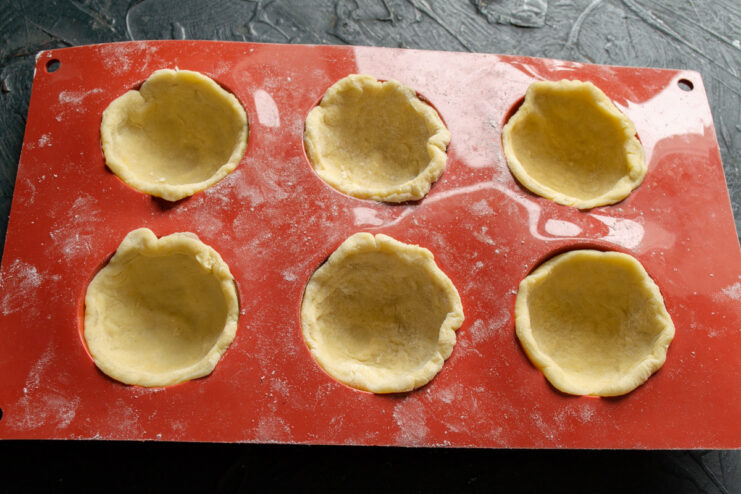 Lining Molds with Dough to Create Cookie Cups Pressing dough circles into a hemisphere silicone mold to form cups.