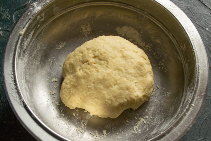Forming the Shortcrust Dough into a Ball A ball of freshly kneaded shortcrust dough on a surface.