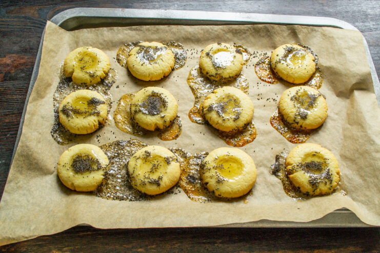 A final bake to set the honey and poppy seed topping. A baking sheet with honey and poppy seed cookies going back into the oven.