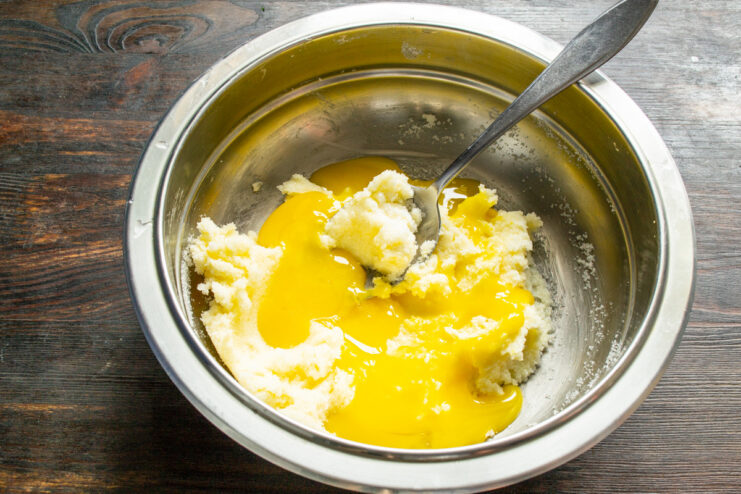 Adding egg yolks to the cookie dough mixture. Separating egg yolks from whites into a small bowl for the cookie recipe.
