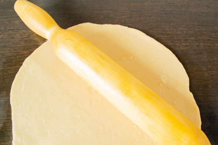 Rolling Out the Chilled Pastry to Cover the Pie Rolling out chilled pastry dough on a surface with a rolling pin.