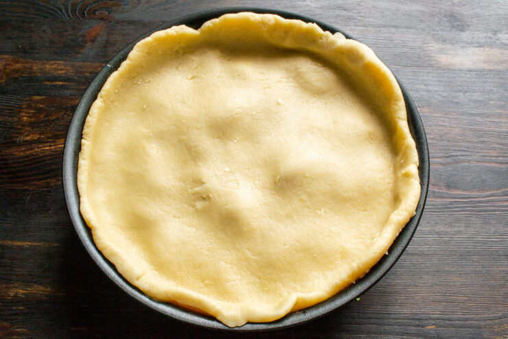 Covering the Apple Filling with Pastry Placing a round sheet of pastry dough over the apple filling in a skillet.