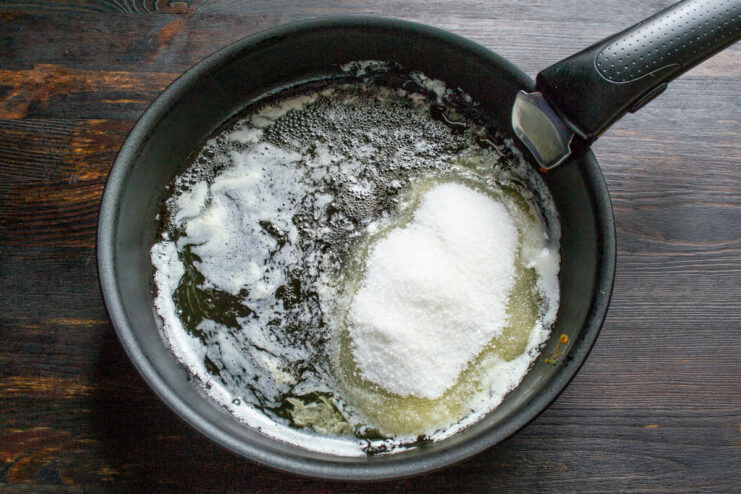 Step 1: Making the Caramel Base for the Apple Pie Butter and sugar melting in a black skillet to create the caramel base for the pie.
