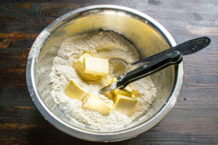 Adding Cold Butter to Flour for a Flaky Pastry Cubed cold butter being added to a bowl of flour and sugar.