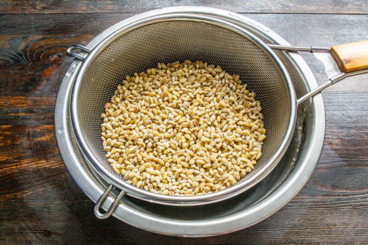 Letting the rinsed pearl barley drain in a sieve. Close-up of rinsed pearl barley draining in a metal sieve.