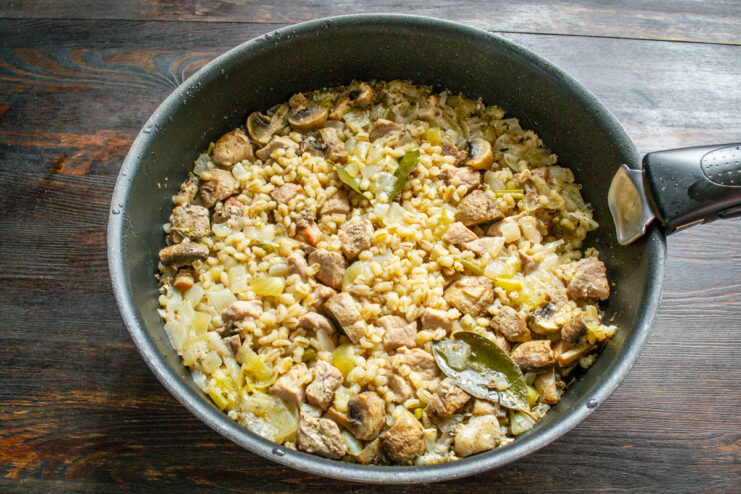 Simmering the dish on low heat for 45-60 minutes. A covered pan simmering on a stove over low heat.