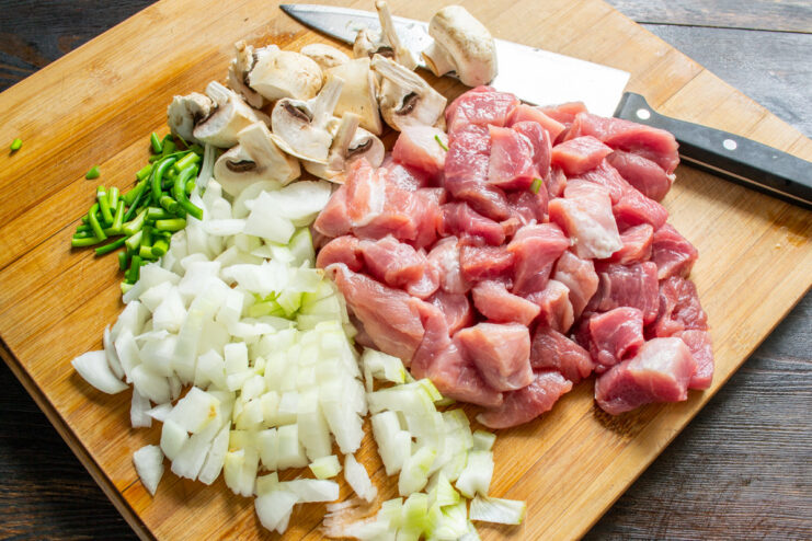 Cubing the lean pork for the pearl barley dish. Lean pork being cut into small cubes on a cutting board.