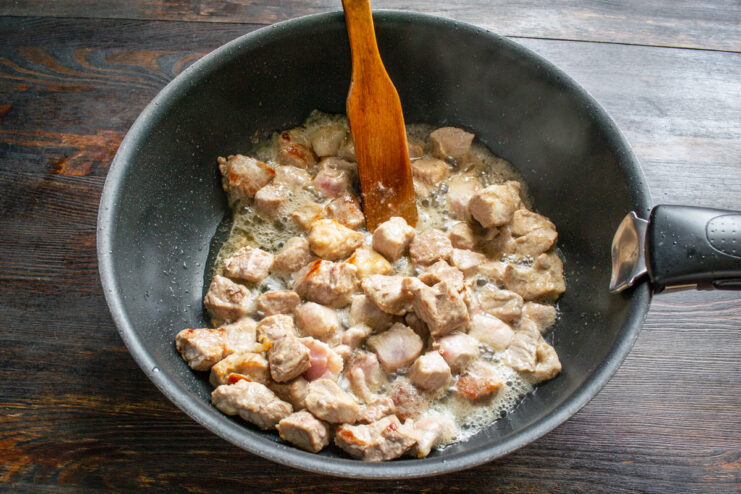 Fry the meat in batches to ensure it browns properly. Golden-brown seared pork pieces in a white bowl.