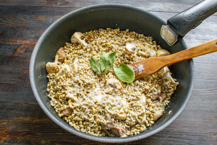 Adding bay leaves on top for extra aroma. Bay leaves placed on top of the pearl barley layer in the pan.