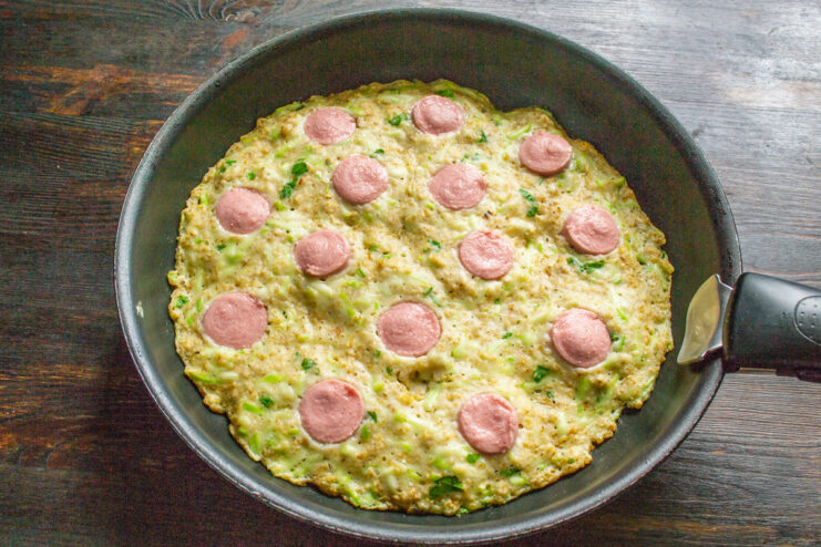 Spreading Tomato Sauce on the Zucchini Pizza Spreading tomato sauce over the partially cooked zucchini pizza crust in a skillet.