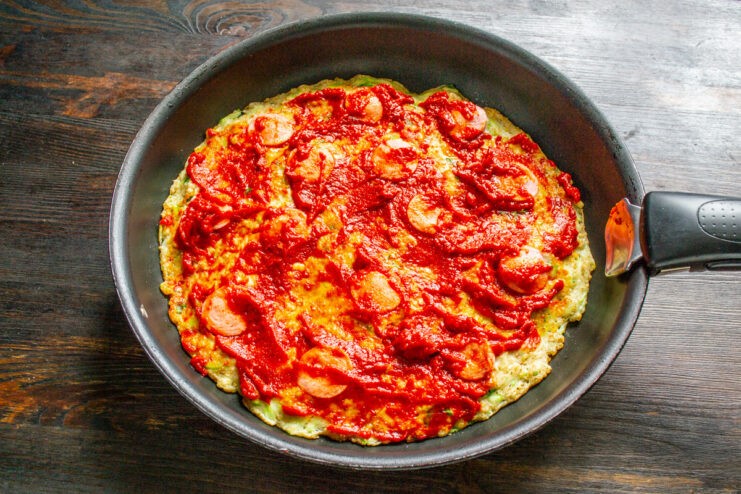 Cooking the Zucchini Pizza on the Stovetop The zucchini pizza cooking in a skillet covered with a glass lid.