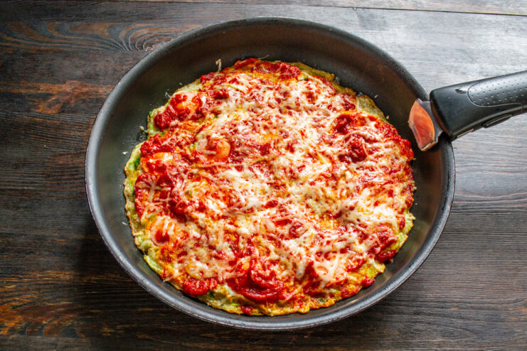 Melting the Cheese on the Skillet Zucchini Pizza The finished skillet zucchini pizza with melted cheese, covered with a lid.