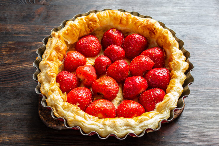 Arranging Fresh Strawberries on the Baked Crust - Creating a beautiful layer of halved berries. Placing halved fresh strawberries, cut-side down, onto the baked puff pastry crust.