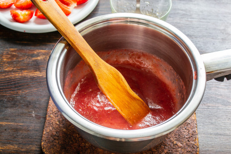 Blending the Strawberry Mixture - Using an immersion blender to create a smooth filling base. Using an immersion blender to puree a mixture of strawberries, sugar, and starch in a bowl.