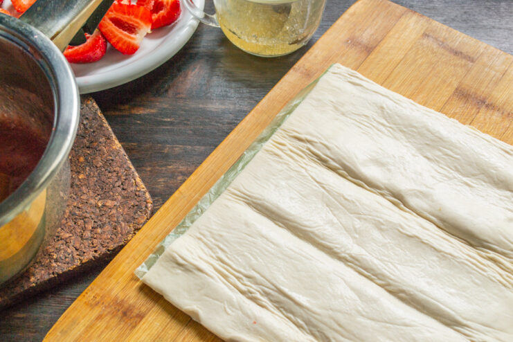 Thawing the Puff Pastry Sheet - Let the dough rest at room temperature before rolling. A sheet of ready-made puff pastry unrolled on a floured surface.