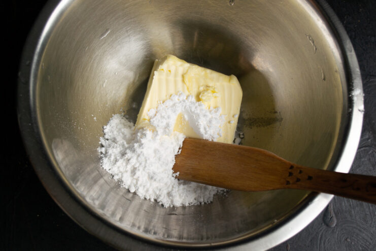 A bowl with softened butter, powdered sugar, and a pinch of salt, ready to be mixed for the pie dough.