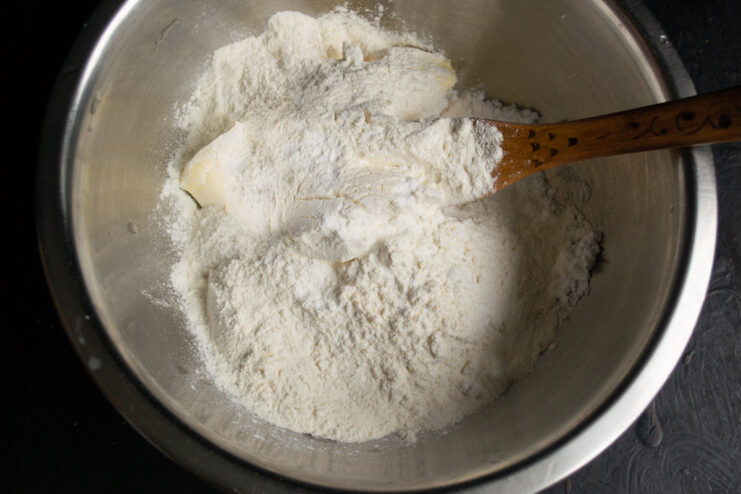 Sifting all-purpose flour into a bowl containing the butter and sugar mixture for the pie crust.