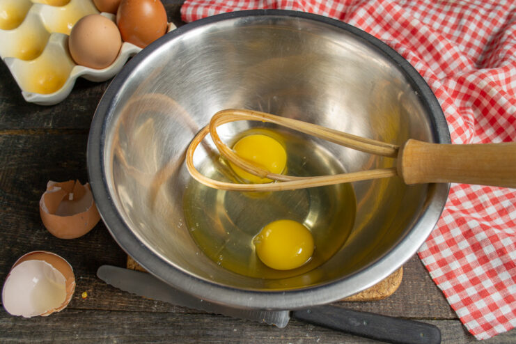 Step 1: Cracking Large Chicken Eggs into a Bowl Two large chicken eggs cracked into a white mixing bowl.