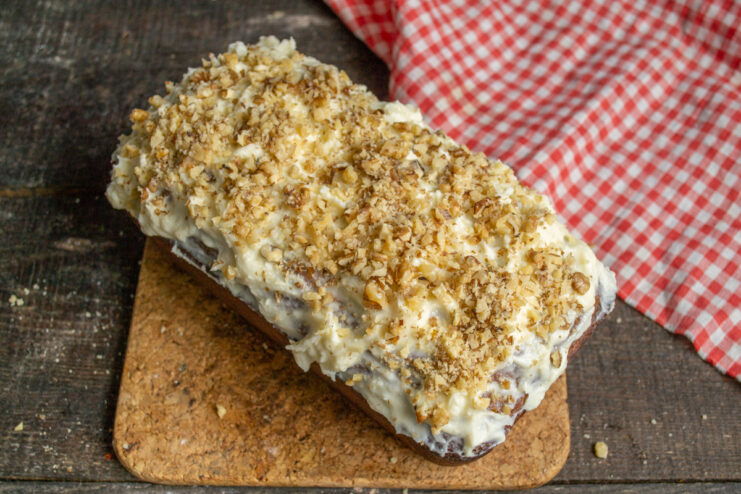 Step 10: Garnishing the Cake with Toasted Walnuts Sprinkling coarsely chopped toasted walnuts over the mascarpone topping on the pineapple cake.