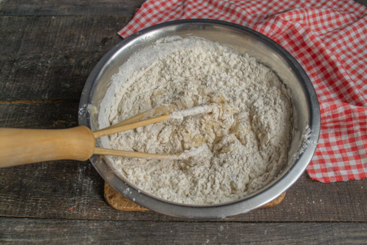 Step 6: Combining Wet and Dry Ingredients to Form the Batter The process of mixing wet and dry ingredients together in a bowl to create the cake batter.