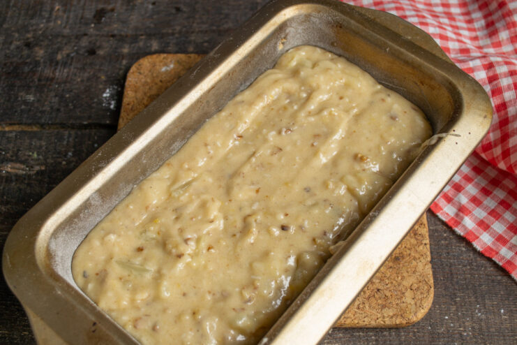 Step 7: Pouring the Batter into the Baking Pan The finished pineapple cake batter being poured into a greased and floured rectangular loaf pan.
