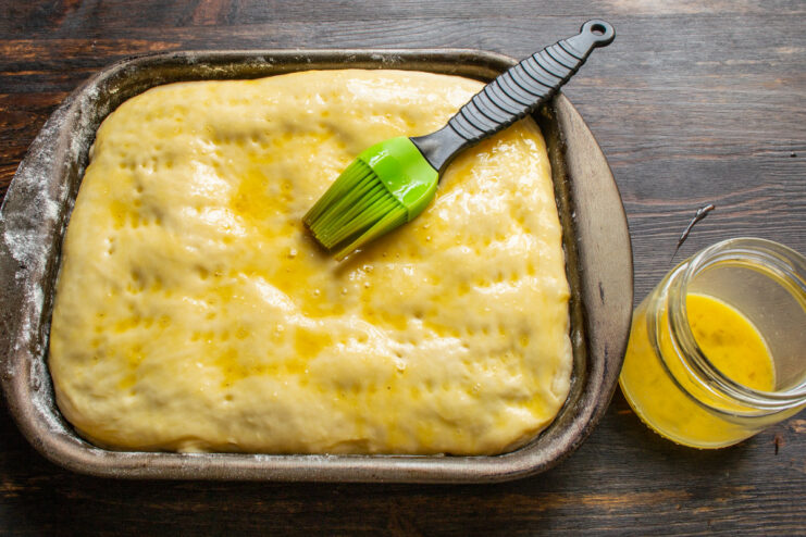 Applying Egg Wash for a Golden-Brown Crust A pastry brush applying egg wash to the top of the proofed cabbage pie.