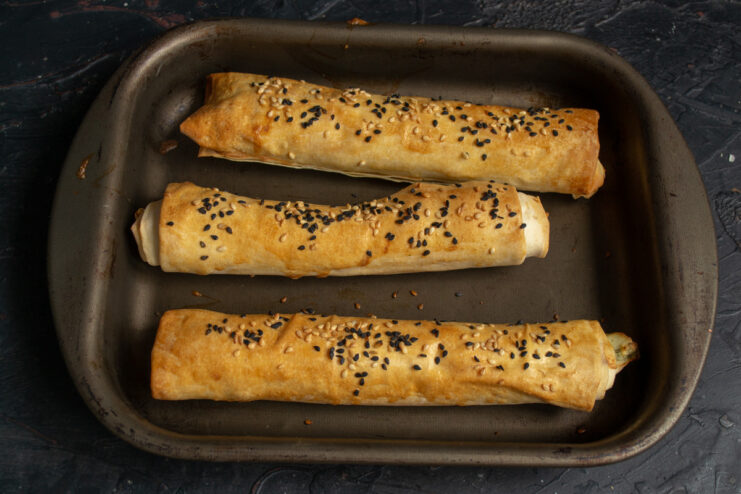 Baking the Pirozhki to Golden Perfection A baking sheet with golden-brown phyllo pirozhki baking inside an oven.