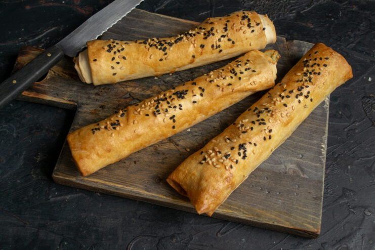 Enjoy These Deliciously Hot and Crispy Pirozhki! A serving plate with freshly baked, golden phyllo pirozhki with brynza, ready to be eaten.