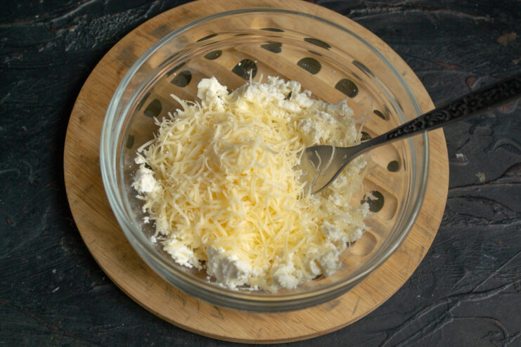 Adding Grated Hard Cheese to the Brynza Finely grated hard cheese being added to a bowl of crumbled brynza.