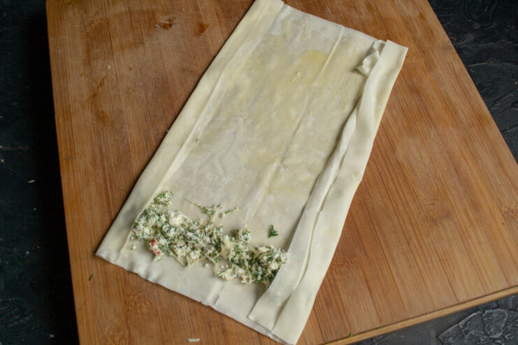 Rolling the Phyllo Dough Pirozhki Folding the sides of the phyllo dough over the filling before rolling it into a tube shape.