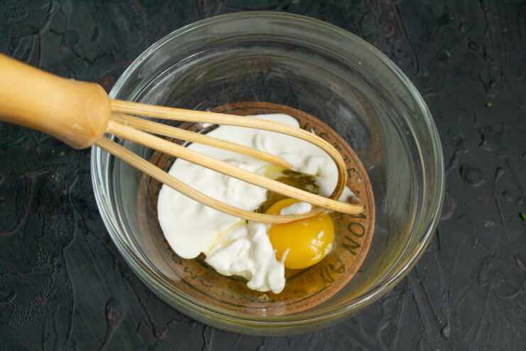 Preparing the Simple Batter for Pirozhki A bowl with an egg, smetana, and salt, ready to be mixed for the pirozhki batter.