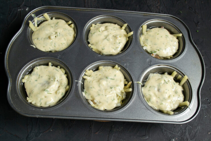 Topping the Pirozhki with Batter Covering the fish and onion filling with the remaining batter in the muffin tin.