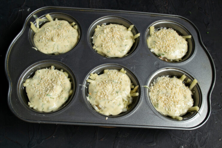 Garnishing with Sesame Seeds Before Baking Sprinkling sesame seeds over the batter-topped pirozhki before baking.