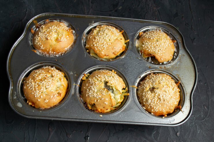 Freshly Baked Golden Pirozhki Ready to Serve Golden-brown saury and potato pirozhki fresh out of the oven in a muffin tin.
