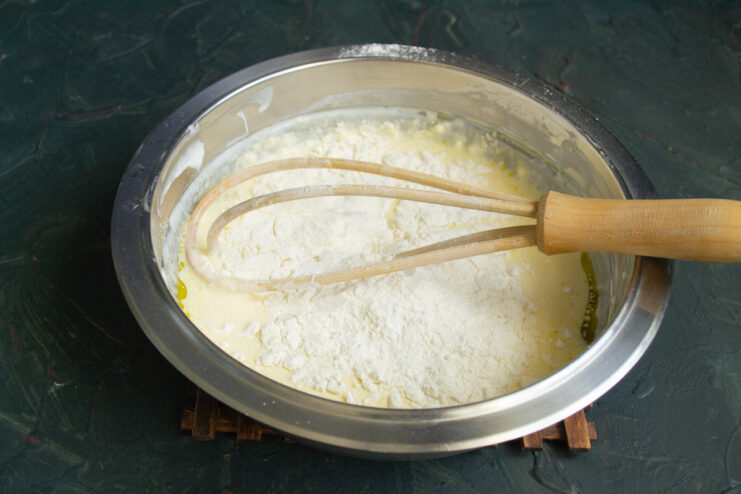 Adding Dry Ingredients to the Batter Adding flour, baking soda, and baking powder to the wet ingredients in a bowl.