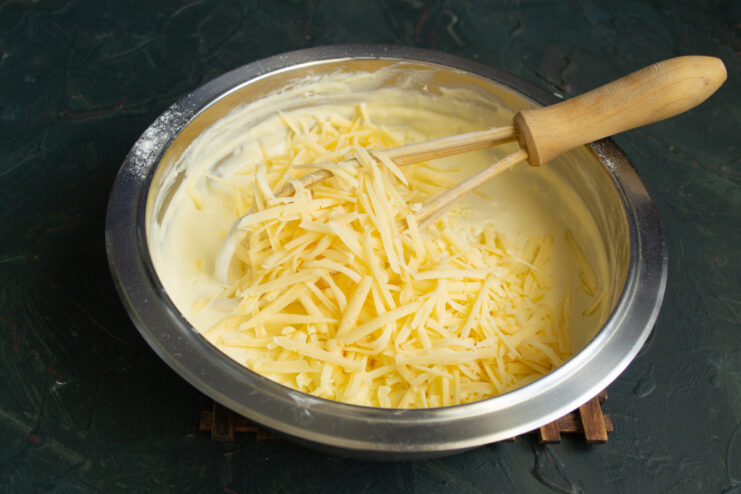 Adding Two Types of Grated Cheese Adding a generous amount of two types of grated cheese to the pirozhki batter.