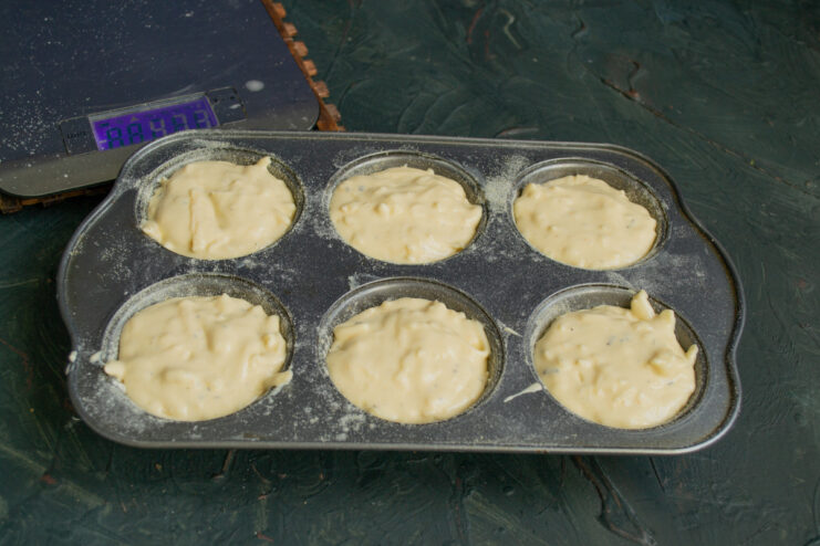 Filling the Muffin Tin with Batter A muffin tin with its cups being filled evenly with the savory cheese batter.