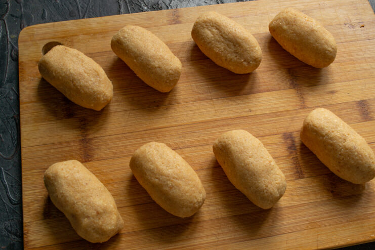 Shaping the dough into potato-like forms Hands shaping the chocolate cake mixture into small, oblong potato shapes.